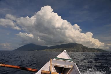 Atauro Island under a towering cloud, seen from the bow of a small boat