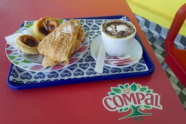 Portuguese custard tarts, a croissant and a cappuccino on a tray in Dili