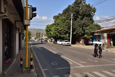 A tree-lined street in central Dili with shops and pedestrians