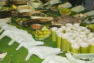 Food laid out on banana leaves at a village gathering in Samalari, Baucau, with drinks and dishes in bamboo tubes