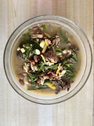 A bowl of Timorese feijoada with beans, meat and greens