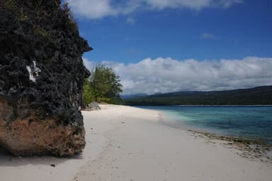 White sand and limestone rock on Jaco Island, with the Lautém coast across the water