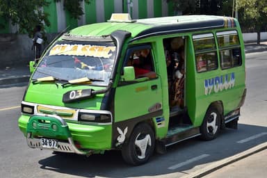 A green mikrolet minibus picking up passengers on a Dili street