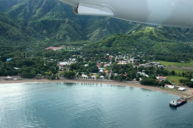 Aerial view of Pante Macassar's bay and town below green hills in Oecusse